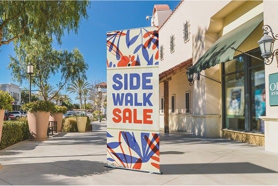 Retractable banner on a sidewalk with sale message